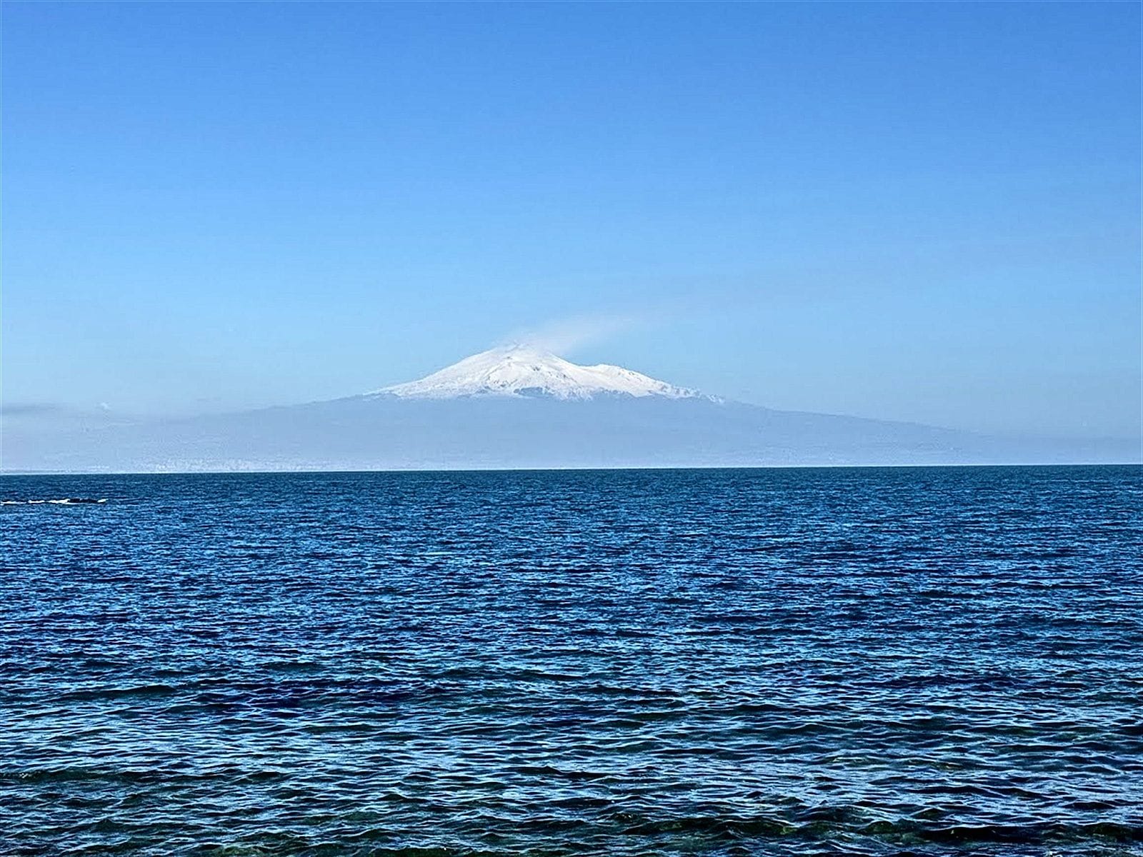 Snow-capped Etna on the horizon across the open sea