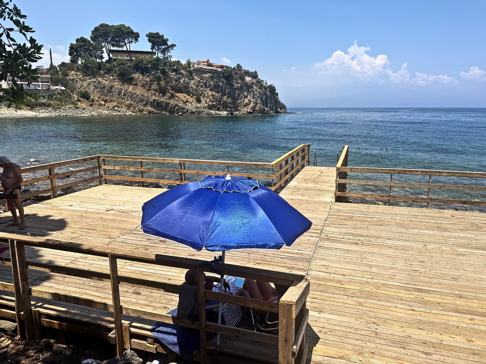 Solarium in legno con ombrellone sulla baia