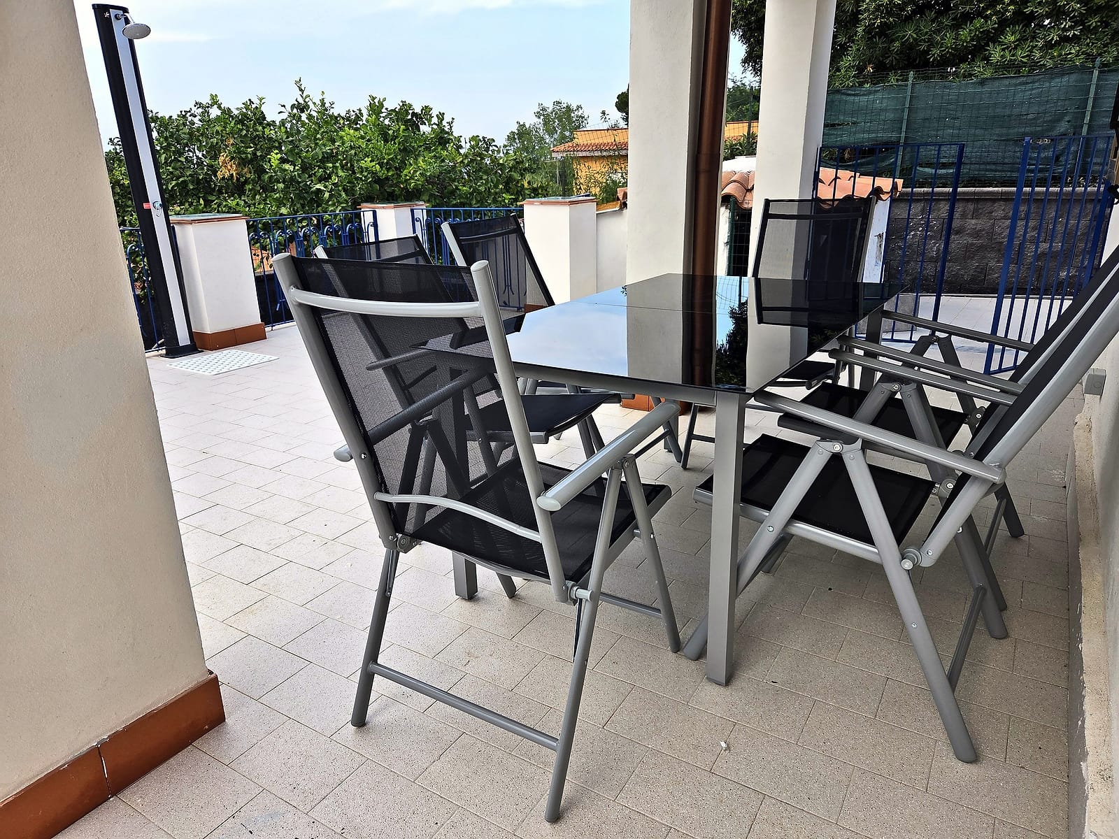 Outdoor table and chairs under the covered veranda, facing the terrace